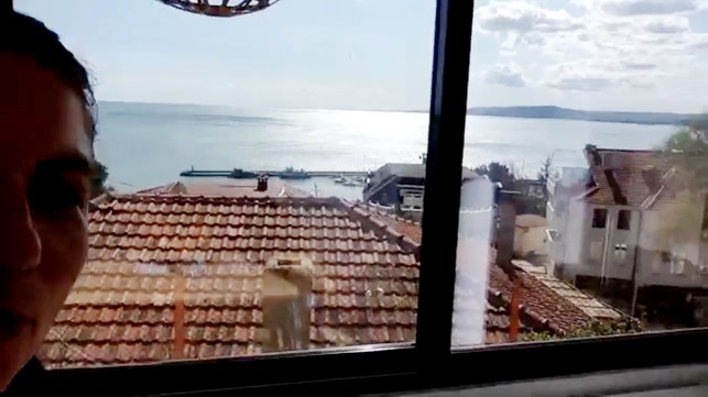 En oplægsholder viser rejsedeltagerne udsigten fra sin lejlighed til Sortehavet.